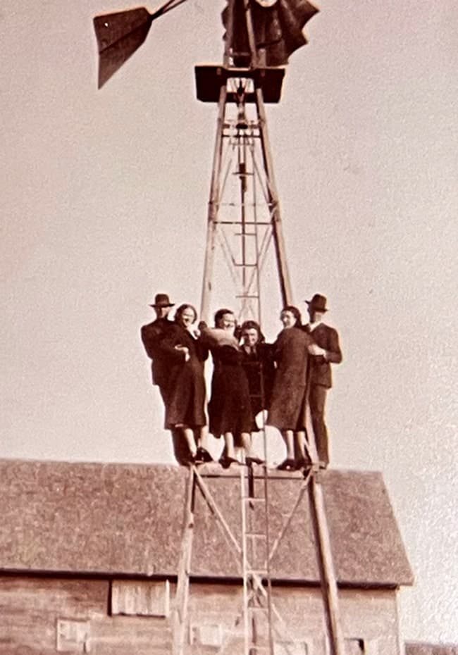 People standing on a windmill in Oklahoma, representing the pioneering spirit of Land Run Distillery
