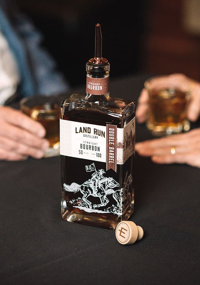 Premium whiskey being poured into a glass, showcasing the rich amber color of Land Run Distillery's bourbon