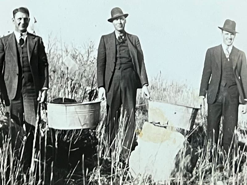 People standing on a windmill in Oklahoma, representing the pioneering spirit of Land Run Distillery