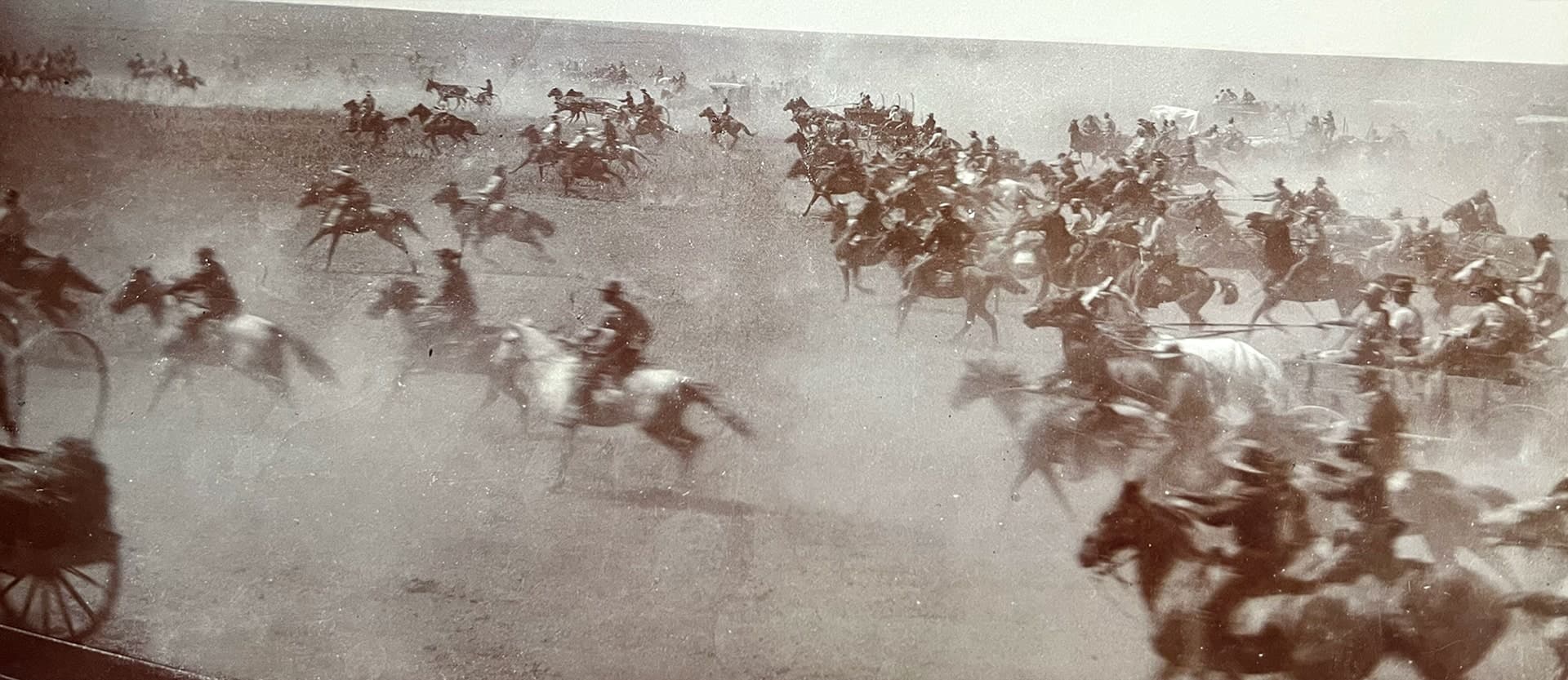 Historic photo of settlers on horseback and wagons racing during the Oklahoma Land Run of 1893 — the bold spirit behind Land Run Distillery.