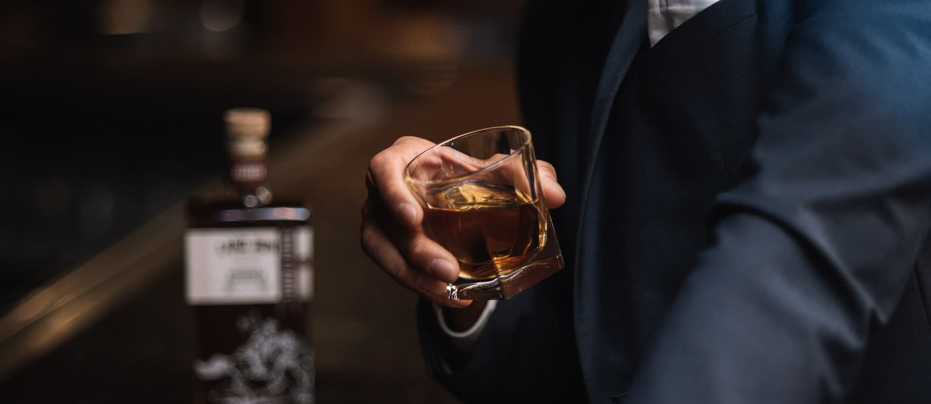 Premium Oklahoma whiskey experience - A connoisseur enjoying Land Run Bourbon at a bar with the signature bottle showcasing our craft spirits